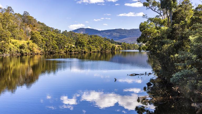 Clouds reflected on the Huon River on a sunny day in Tasmania