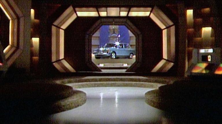 Shot of the interior of the studio of Sale of the Century. A blue car is being revealed through a lit up window.