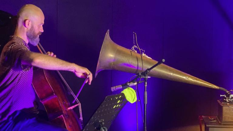 Christopher Pidcock plays the cello into a large gramophone horm, to record a wax cylinder.