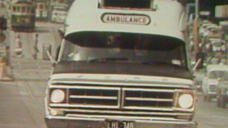 A 1970s ambulance driving to an accident scene.