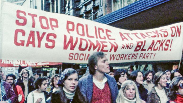 A Sydney protest march in the late 1970s with young people walking under a banner that reads 'Stop police attacks on gays, women and blacks!'
