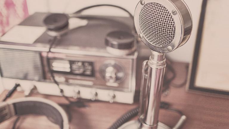 A radio microphone and audio recorder sitting on a desk.
