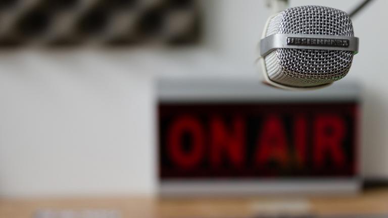 A radio microphone in front of an On Air sign in a radio station studio
