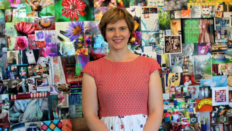 Beth Taylor standing in front of her exhibition of 1000 photos on the topic of 'home'