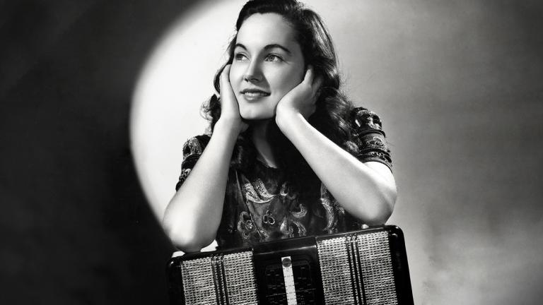 Black and white portrait of actress Betty Bryant wit her elbows resting on a piano accordian and her face in her hands.