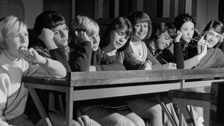 Eight young people sit at a long table. One of them is Debra Byrne who is smiling at the camera.