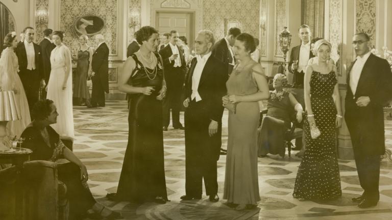 A large ballroom full of people in elegant clothing.