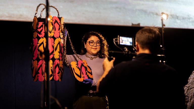 Curator Vick Gwyn being filmed while standing next to, and talking about, the Thong Dress from the film The Adventures of Priscilla, Queen of the Desert