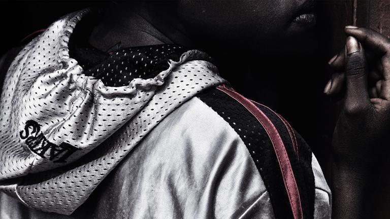 A young Aboriginal man wearing an athletics hoodie and looking away from the camera