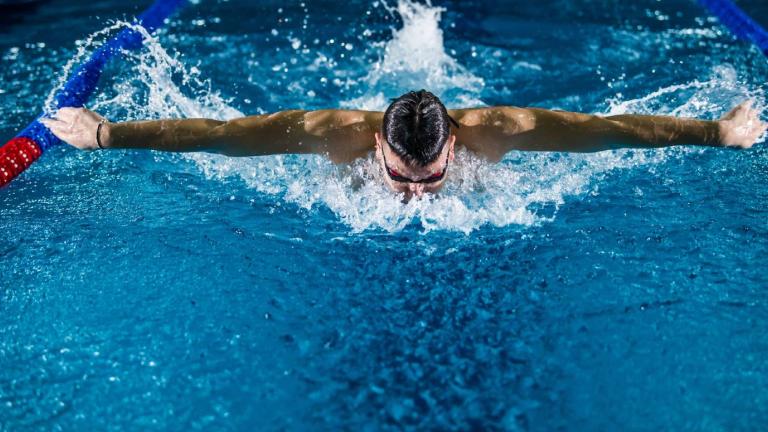 A man swimming a butterfly stroke in an Olympic pool
