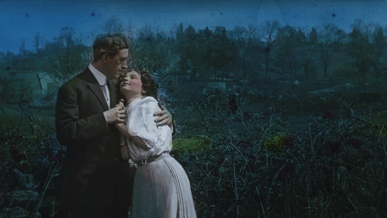 Glass slide image of a man and woman in an embrace standing in the moonlight, circa 1906.