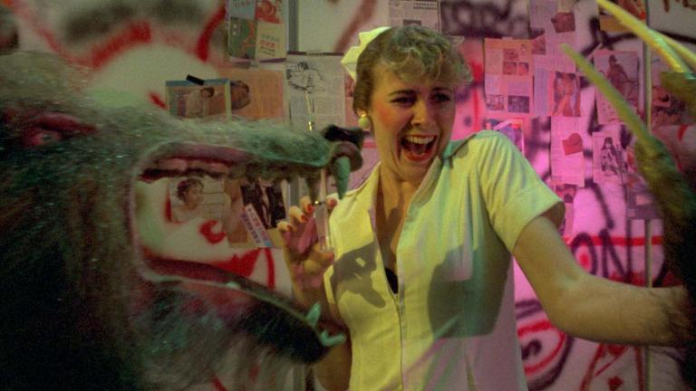 A nurse holding a syringe screams as she is menaced by a werewolf