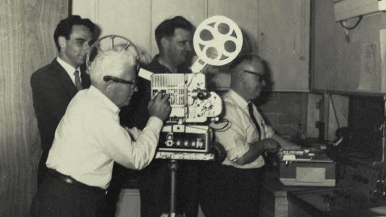 Four men operating a film projector