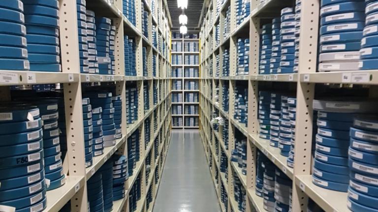 Rows of shelving stacked with film canisters in the NFSA vaults