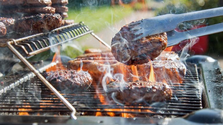 Close up of a barbecue grill with burger patties cooking on it.