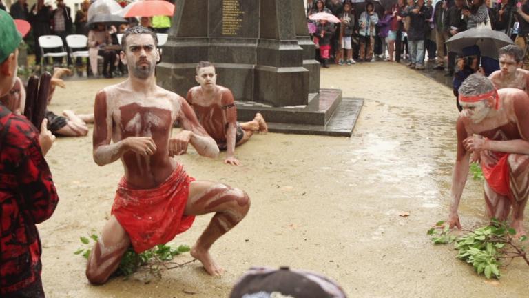 Indigenous dancers performing in front of a war cenotaph 