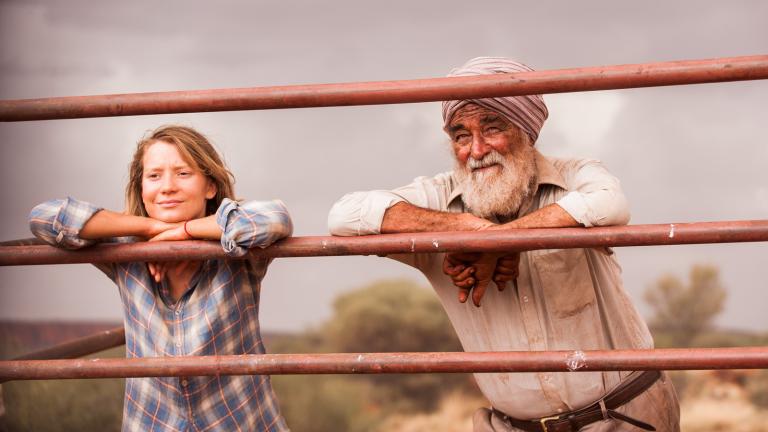 Mia Wasikowska and John Flaus leaning on a fence in a scene from the movie Tracks Mia Wasikowska and John Flaus leaning on a fence in a scene from the movie Tracks
