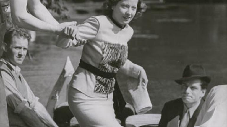 Merle Oberon helped into a boat Merle Oberon is helped into a small boat on a river