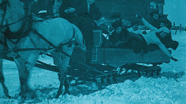 A group of men and women in the back of a horse drawn cart in the snow.