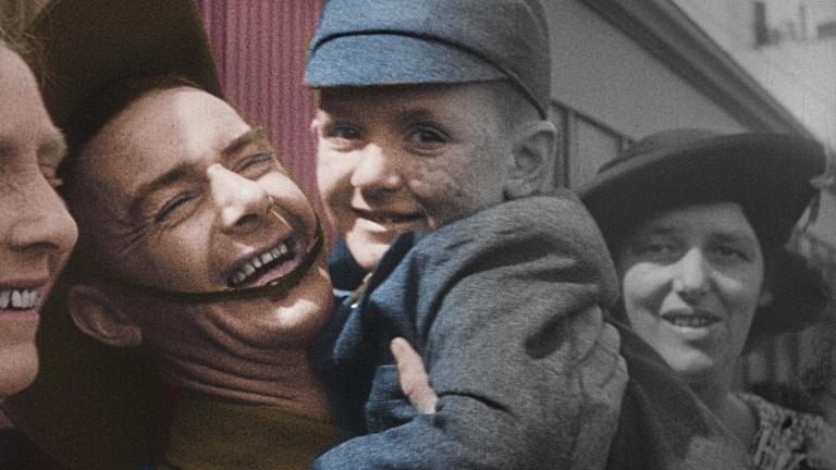 A partially colourised image of a laughing Australian soldier on leave holding up a smiling boy