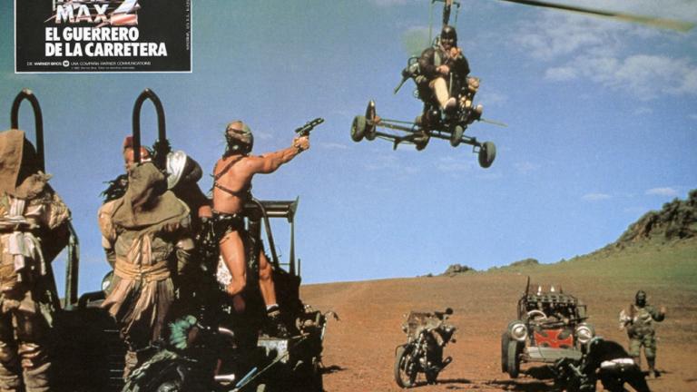 Mad Max 2 lobby card shows Humungus (Kjell Nilsson) shooting at the Gyro Captain (Bruce Spence) as he flies overhead.