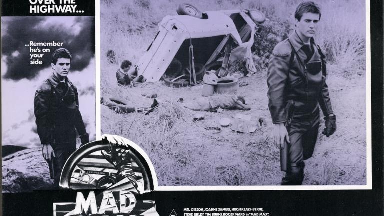 Lobby card for Max Max shows Max (Mel Gibson) next to an overturned car Lobby card for Max Max shows Max (Mel Gibson) next to an overturned car