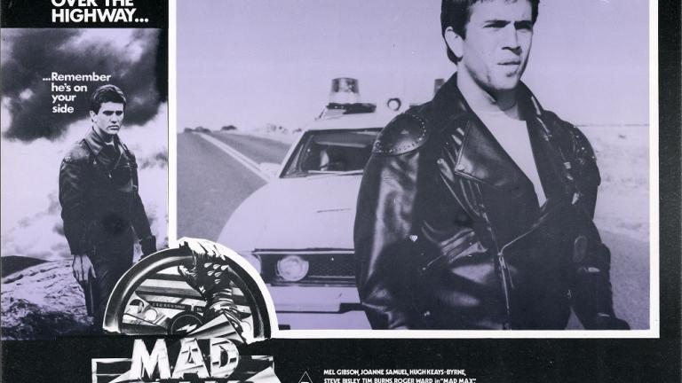 Lobby card for Max Max shows Max (Mel Gibson) standing on a highway with a police car behind him. Lobby card for Max Max shows Max (Mel Gibson) standing on a highway with a police car behind him.
