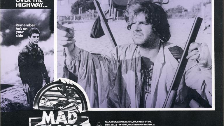 Lobby card for Max Max shows Toecutter (Hugh Keays-Byrne) pointing and holding a rifle. Lobby card for Max Max shows Toecutter (Hugh Keays-Byrne) pointing and holding a rifle.