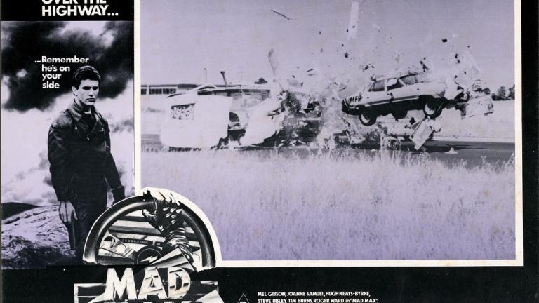 Max Max 1 lobby card shows a car flying through the air and smashing though a caravan. Max Max 1 lobby card shows a car flying through the air and smashing though a caravan.