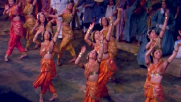 Rows of dancers in bright orange costumes.