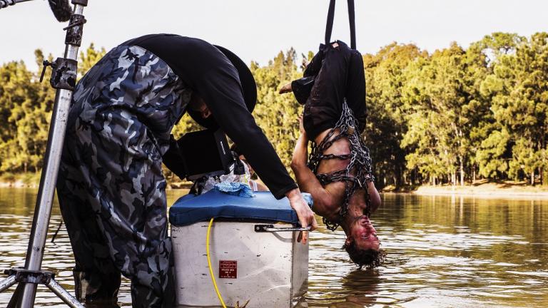 Production shot of a man suspended over a river 