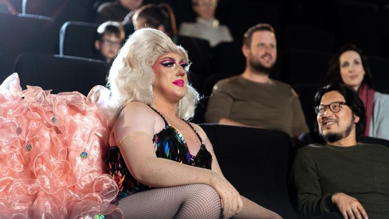 Drag queen Toni Kola in costume seated in a cinema with NFSA staff