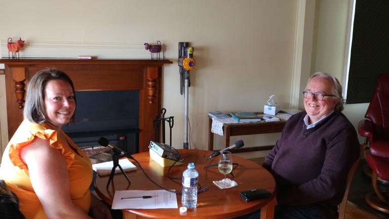 A woman and man sit on opposite sides of a small table in a living room.
