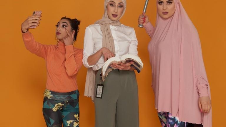 Three Muslim women, one looking at her mobile phone, another with a text book and the third brandishing a baseball bat