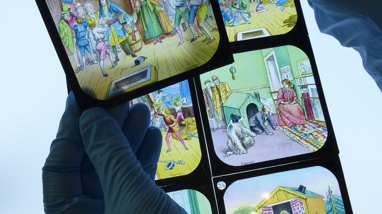 Curator examining glass slides of the childrens story of Peter Pan on a lightbed.