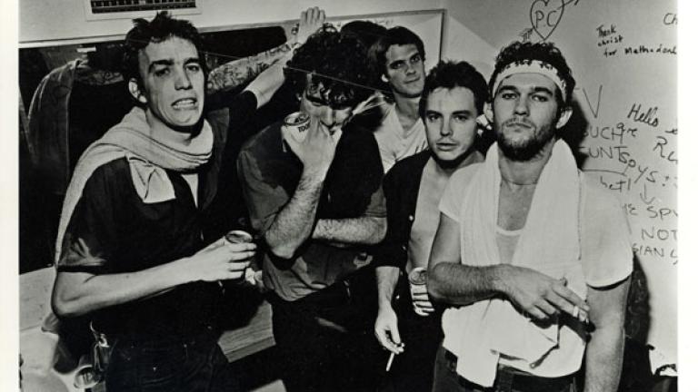The five band members of Cold Chisel photographed backstage at the Manly Vale hotel against a graffitied wall. Circa 1980. 