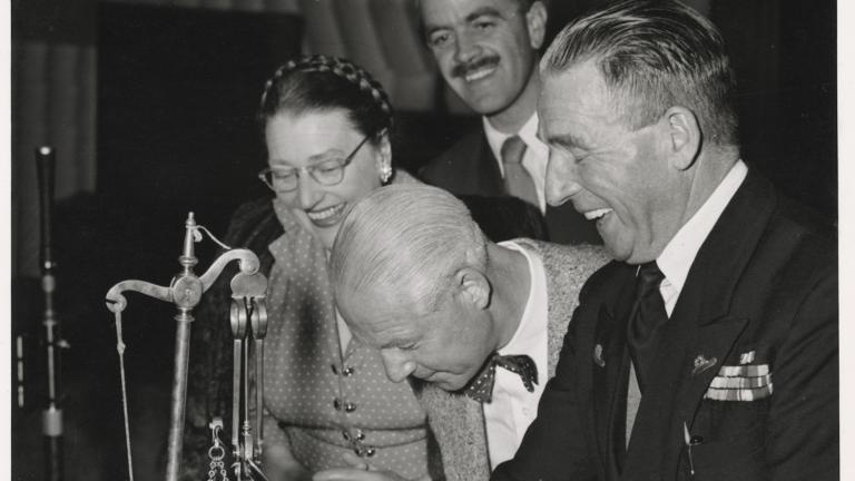 A woman and three men looking at a large bar of soap on a scale