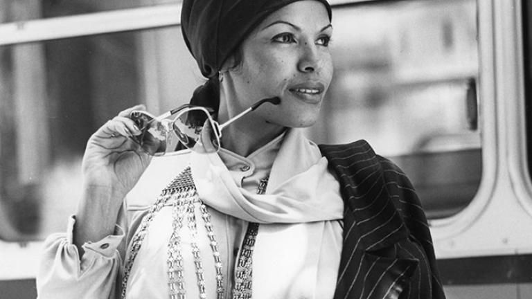 Black and white image of Wilma Reading wearing a scarf and holding a pair of sunglasses