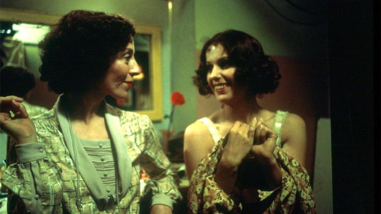 Film still of Melissa Jaffer as Leslie with Helen Morse as Caddie. Both women appear carfree and smile at each other.