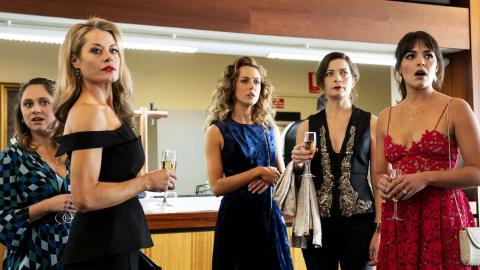 A group of five women in formal attire looking shocked