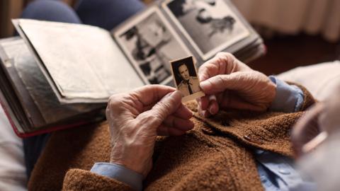 An elderly person looking at an old photo album