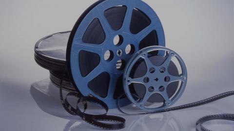 Two film canisters sit on a table service with the film partially unwound.