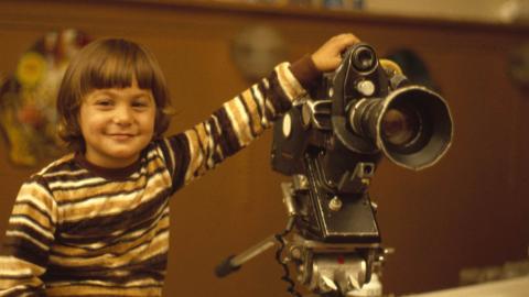 A young boy holds a camera in the 1960s