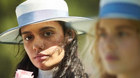 Two girls wearing white broadbrimmed hats with a blue band