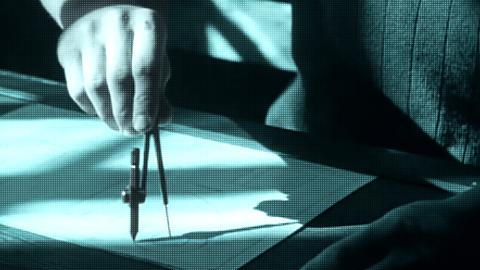 A hand holding a mathematical compass on a sheet of paper. 