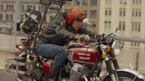 A man rides a motorcycle with a camera mounted on the back.