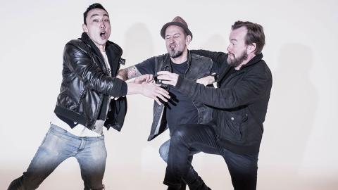 Three band members from Regurgitator comically pushing and shoving each other. 