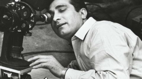 A man leaning over and looking into a movie camera