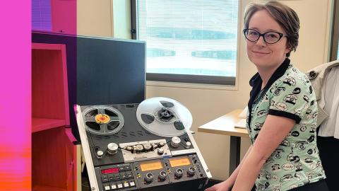 NFSA curator Amy Butterfield, seated and looking up at the camera. She is sitting next to some audio equipment
