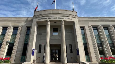 Front of NFSA building images is angled upwards to see blue sky. Pots with red tulips sit either side of steps